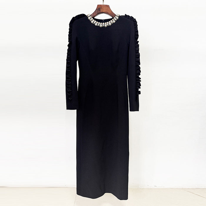 Black dress with ruffled sleeves on a wooden hanger against a white background