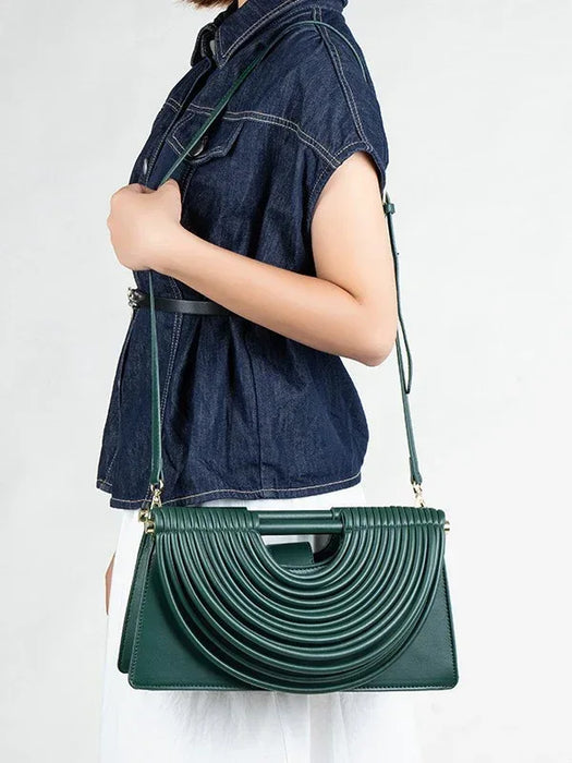 Person wearing a dark denim shirt with a green handbag over their shoulder on a white background