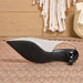 A single women's slingback heel shoe shown from the side, featuring a textured light beige upper, a black sole, and a glossy black heel, resting on a woven rug with a boho-style background.