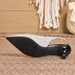 A single women's slingback heel shoe shown from the side, featuring a textured light beige upper, a black sole, and a glossy black heel, resting on a woven rug with a boho-style background.