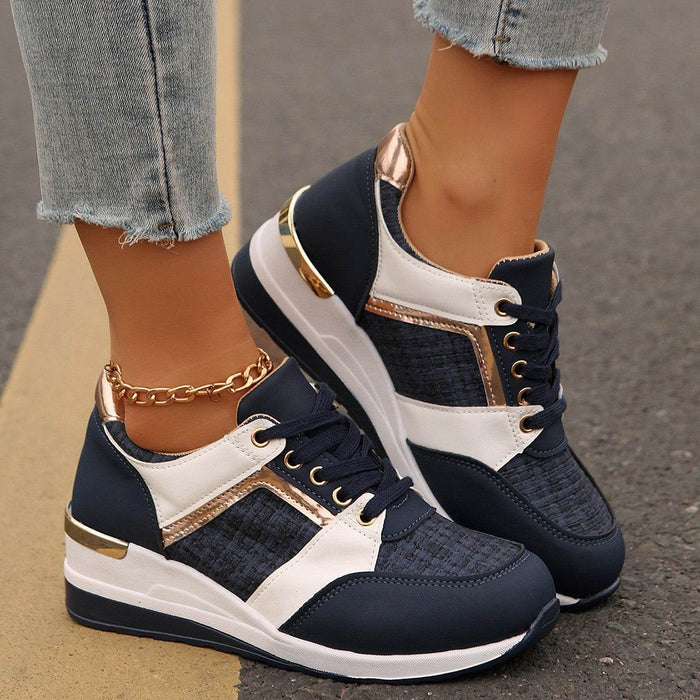 Navy and white sneakers with gold accents worn by a person on a blurred street background