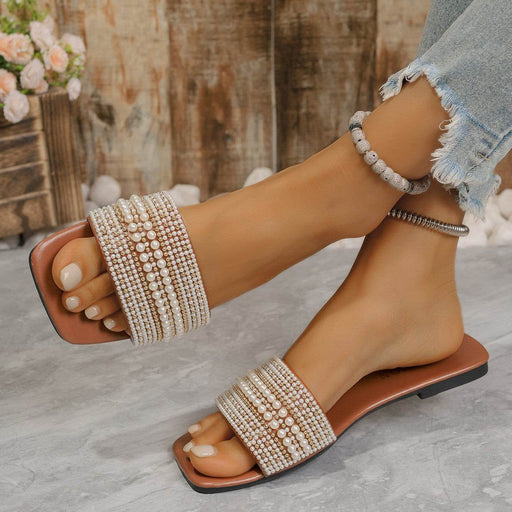 Brown sandals with pearl embellishments worn by a person on a neutral background
