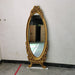 Decorative gold mirror with intricate designs on a white wall.
