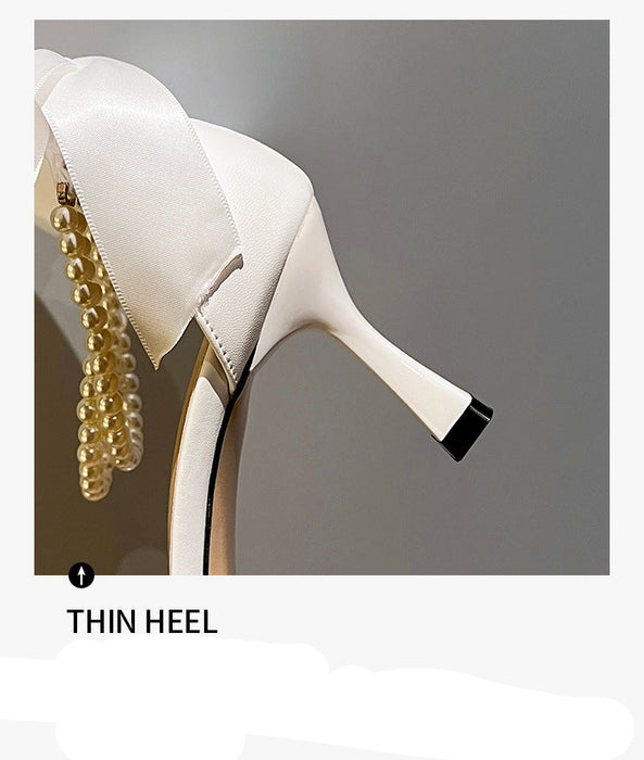 White high-heeled shoe with pearl details on a gray background