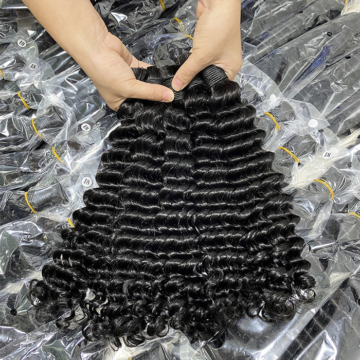 Person holding a bundle of curly hair extensions on a background of similar hair extensions.