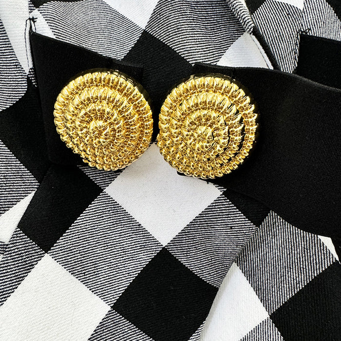 Gold textured earrings on a black and white checkered background
