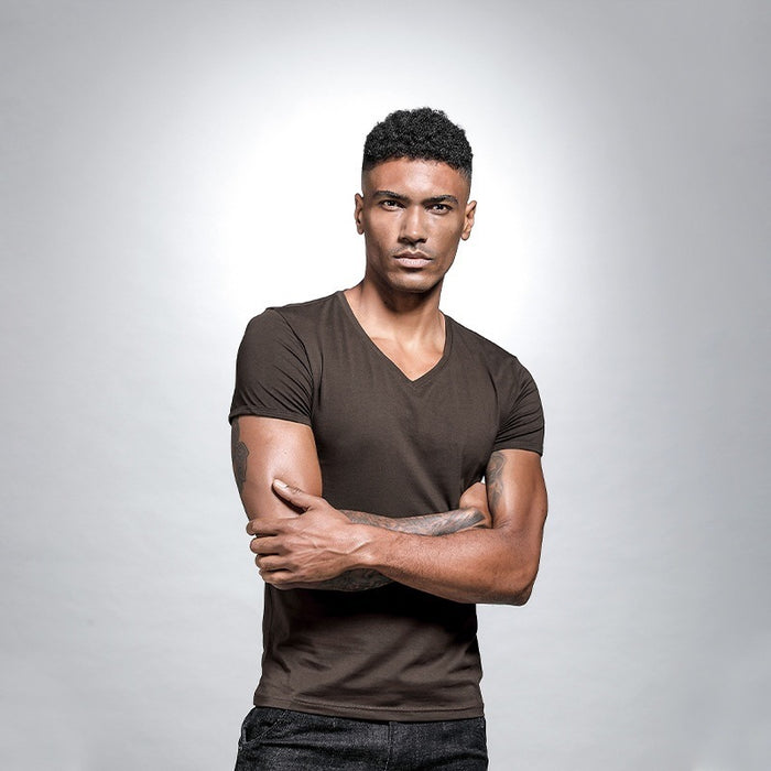 Man wearing a brown t-shirt against a gray background