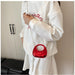 Person wearing a white sweatshirt with red text, holding a red handbag.