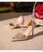 Pair of embellished high-heeled shoes on a textured surface with a decorative background.