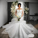 Bride in a white wedding dress holding a bouquet in a decorated room.