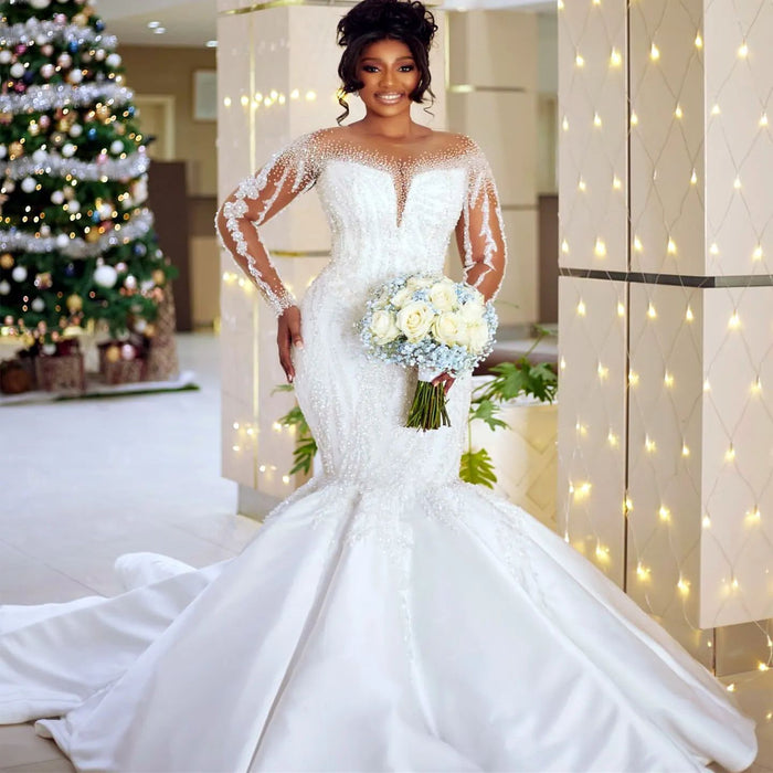 Woman in a white wedding dress holding a bouquet in a decorated room with lights and a Christmas tree.
