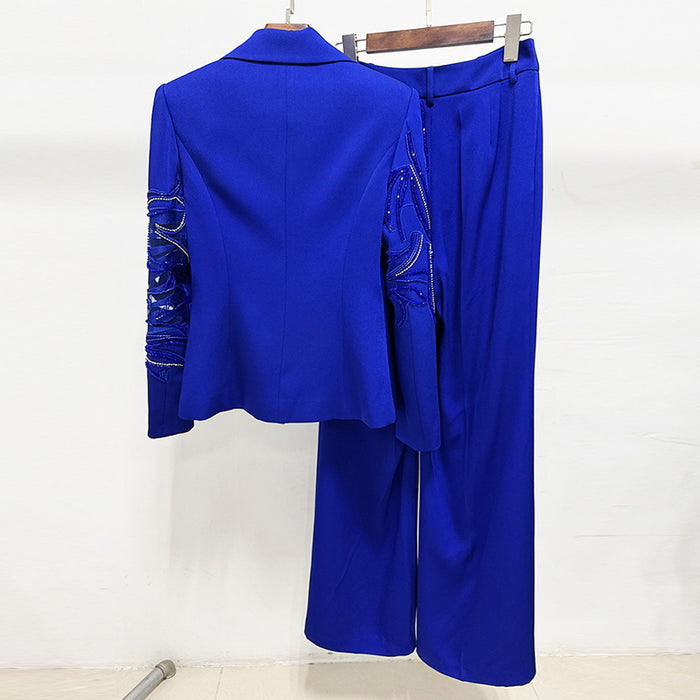 Blue outfit with embroidered sleeves on a hanger against a white background