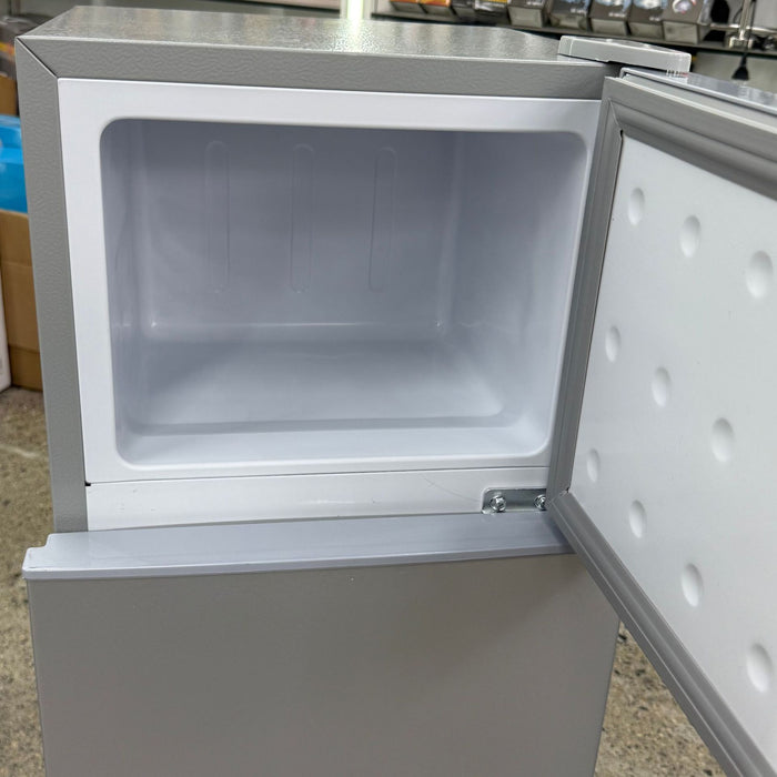 Small white refrigerator with open door on a countertop
