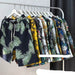 Collection of tropical patterned shirts on a rack against a dark curtain.