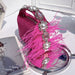 Pink sandal with feather details and pearls on a reflective surface