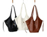 Three handbags in black, white, and brown hanging against a white background