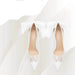 White high-heeled shoes with lace details on a light background