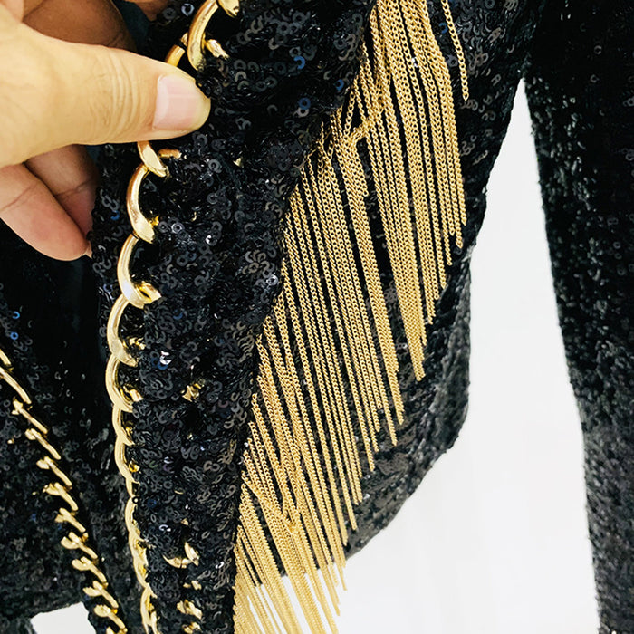 Black sequined clutch with gold fringe and a hand holding it.