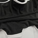 Close-up of a black garment with white trim on a white background