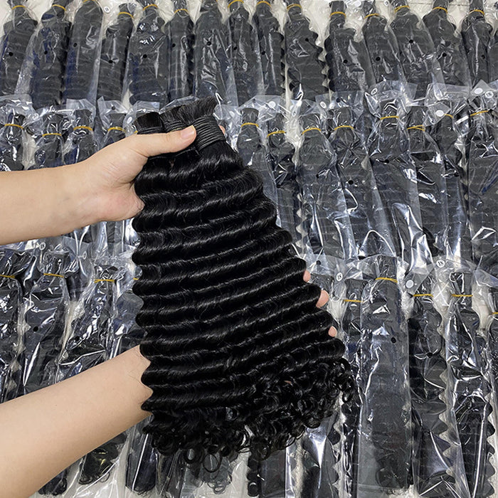 Person holding a bundle of black hair extensions with a background of more hair extensions in packaging.