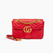 Red quilted handbag with gold chain and logo on a white background