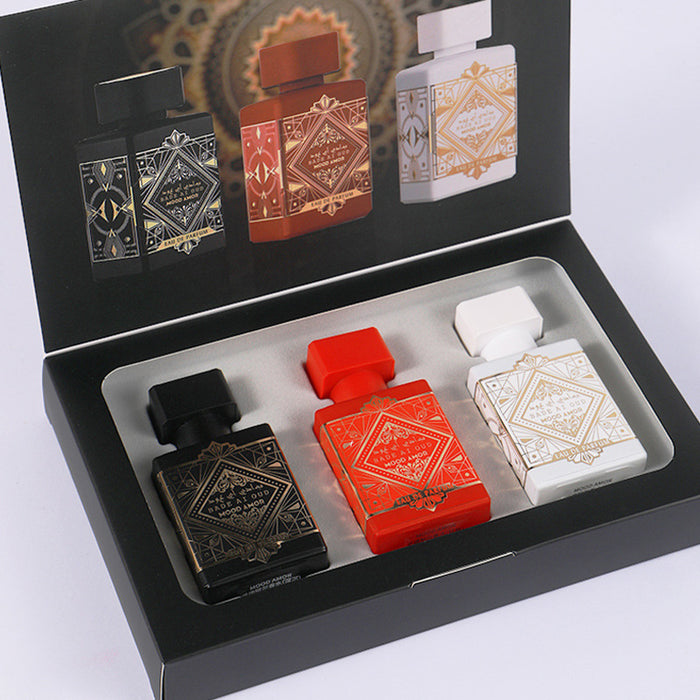 Set of four perfume bottles in a black box on a white background