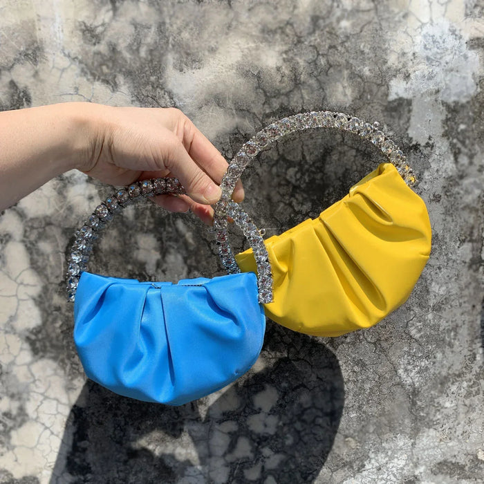 Two small fabric bags, one blue and one yellow, held against a marble background.