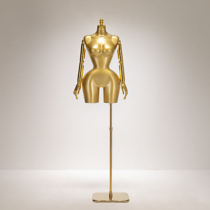 Gold mannequin on a stand against a gray background