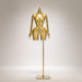 Gold mannequin on a stand against a gray background