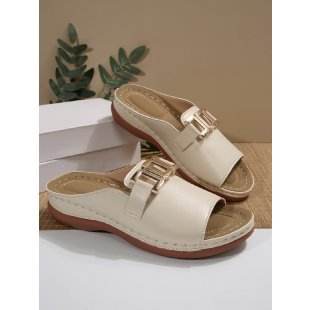 Pair of beige sandals with gold buckles on a neutral background