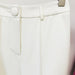 Close-up of white pants with a button and belt on a light background