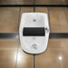 White bidet attached to a wall with black seat cover on a tiled bathroom floor.