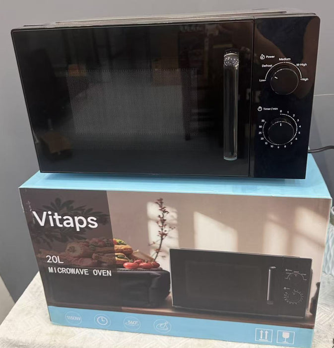A black Vitaps 20L microwave oven sits on top of its blue and white retail box. The microwave has a glossy black finish with a silver handle and control knobs on the right side.
