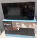 A black Vitaps 20L microwave oven sits on top of its blue and white retail box. The microwave has a glossy black finish with a silver handle and control knobs on the right side.