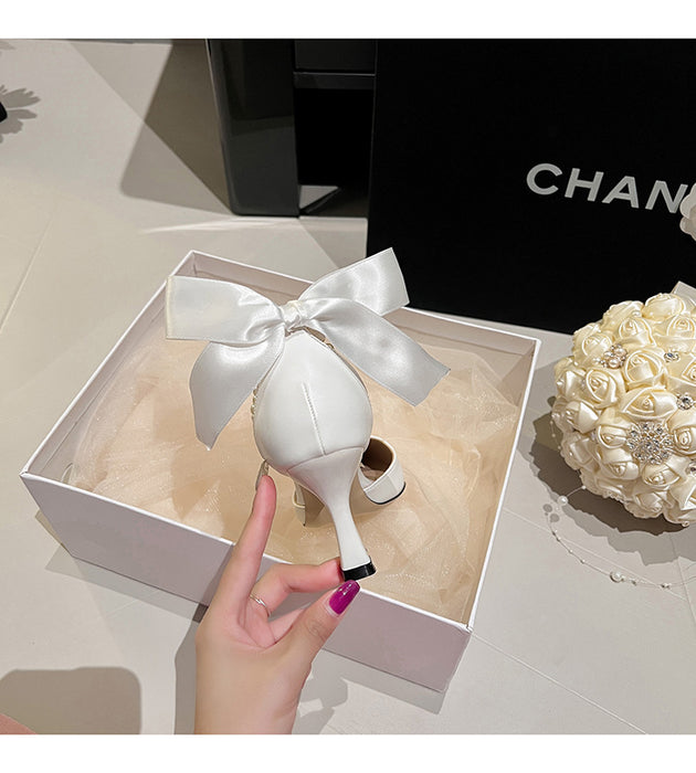 White decorative item with a bow in a Chanel box on a light surface.