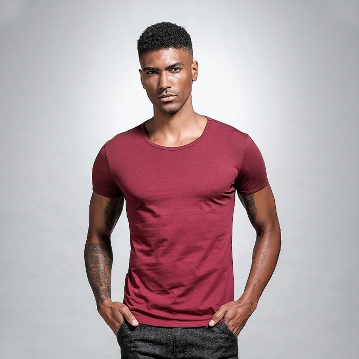 Man wearing a maroon t-shirt against a gray background