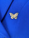 Gold butterfly pin on a blue fabric background
