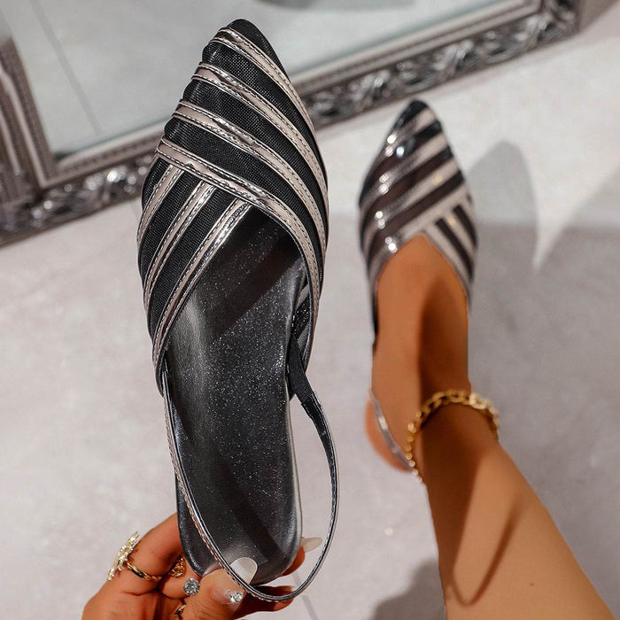 Black and silver striped sandal held by a hand with a blurred background