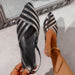 Black and silver striped sandal held by a hand with a blurred background
