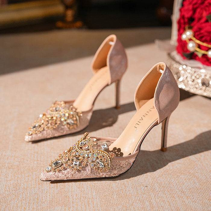 Pair of embellished high-heeled shoes on a textured surface with a blurred background