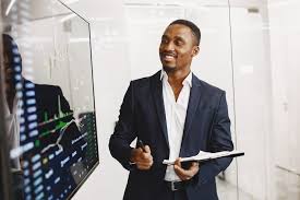 Man in a suit holding a tablet in front of a screen displaying financial data.